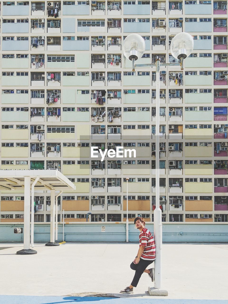 Side view full length of young man standing against buildings in city