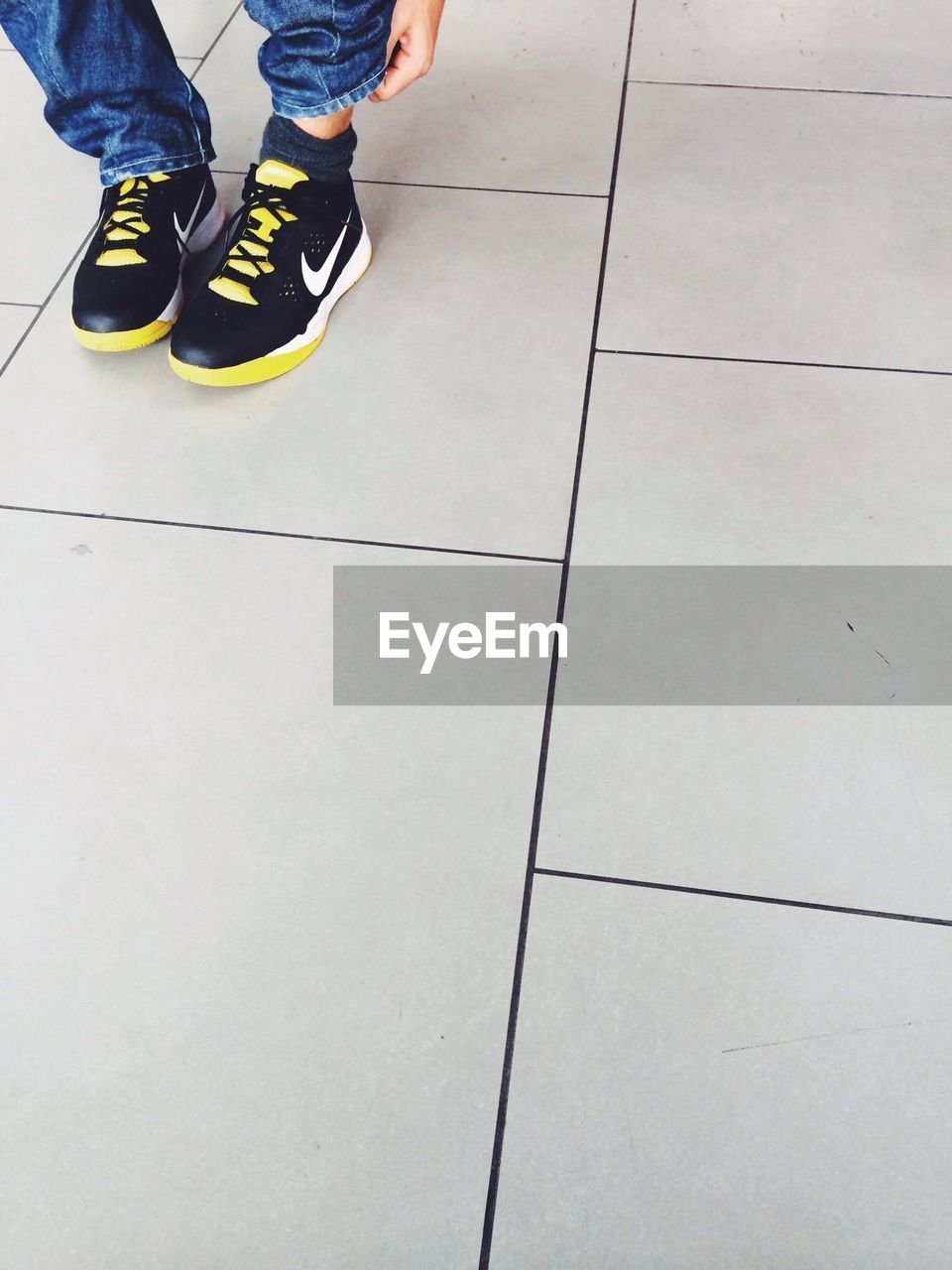 LOW SECTION OF WOMAN STANDING ON TILED FLOOR