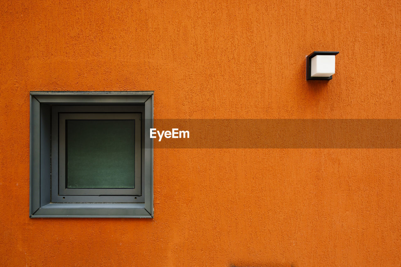 Low angle view of window on orange wall