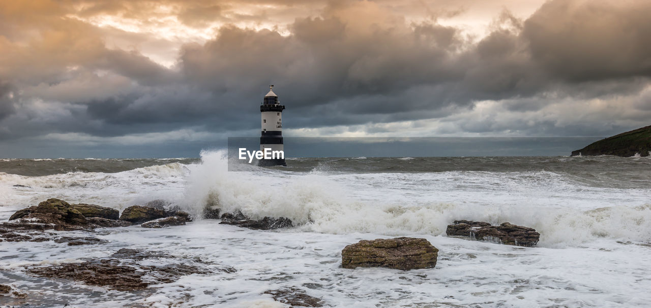 Lighthouse by sea against sky