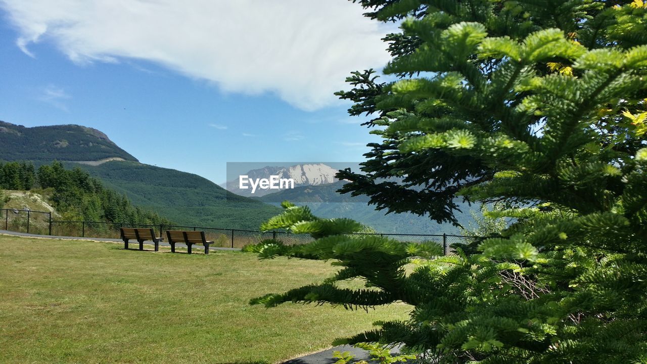 View of empty benches on landscape against mountain ranges