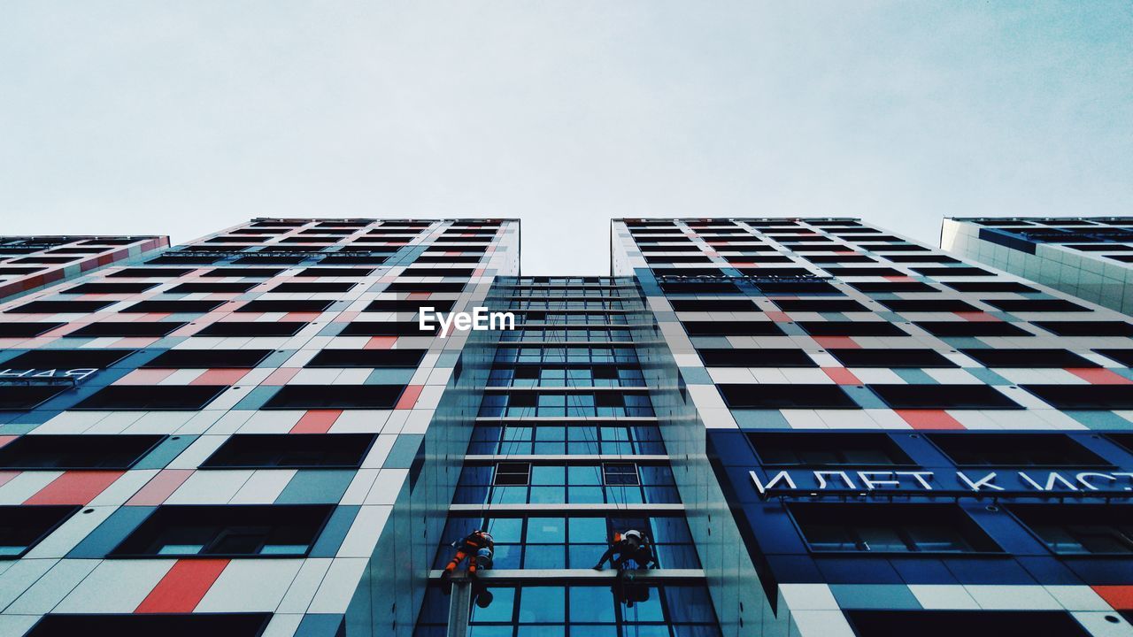 LOW ANGLE VIEW OF GLASS BUILDING AGAINST CLEAR SKY