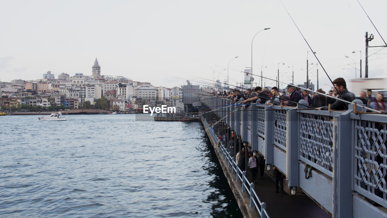 Boats in river by buildings against clear sky