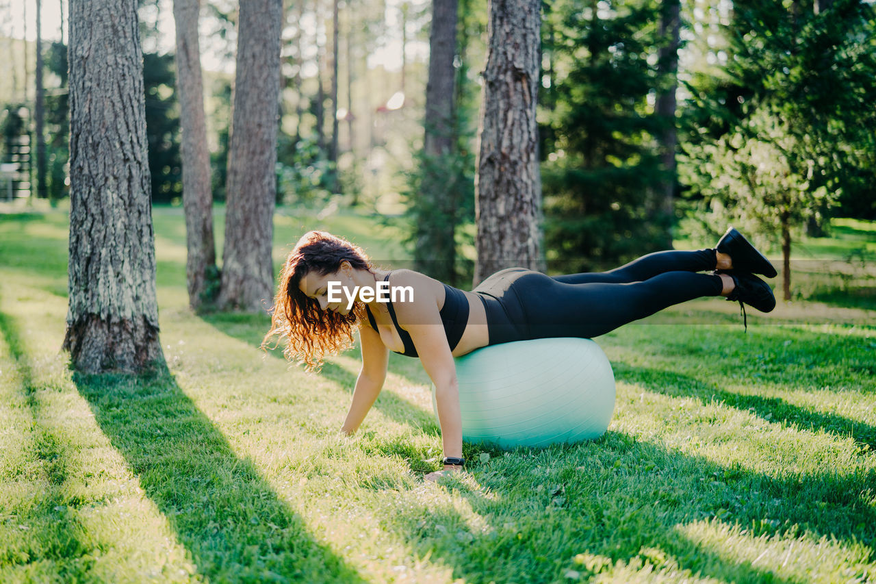 Full length of woman exercising with fitness ball at park