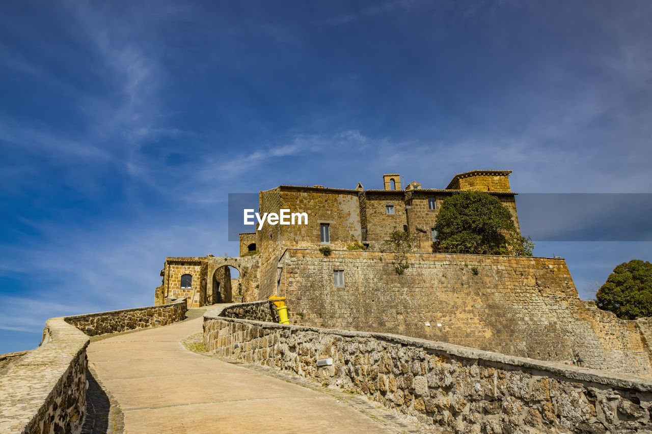 architecture, history, the past, sky, built structure, ancient, fort, travel destinations, fortification, building exterior, cloud, travel, castle, nature, wall, old ruin, building, ruins, fortified wall, old, medieval, tourism, blue, ancient history, staircase, landmark, sea, stone material, no people, outdoors, surrounding wall, ancient civilization, city, tower, rock