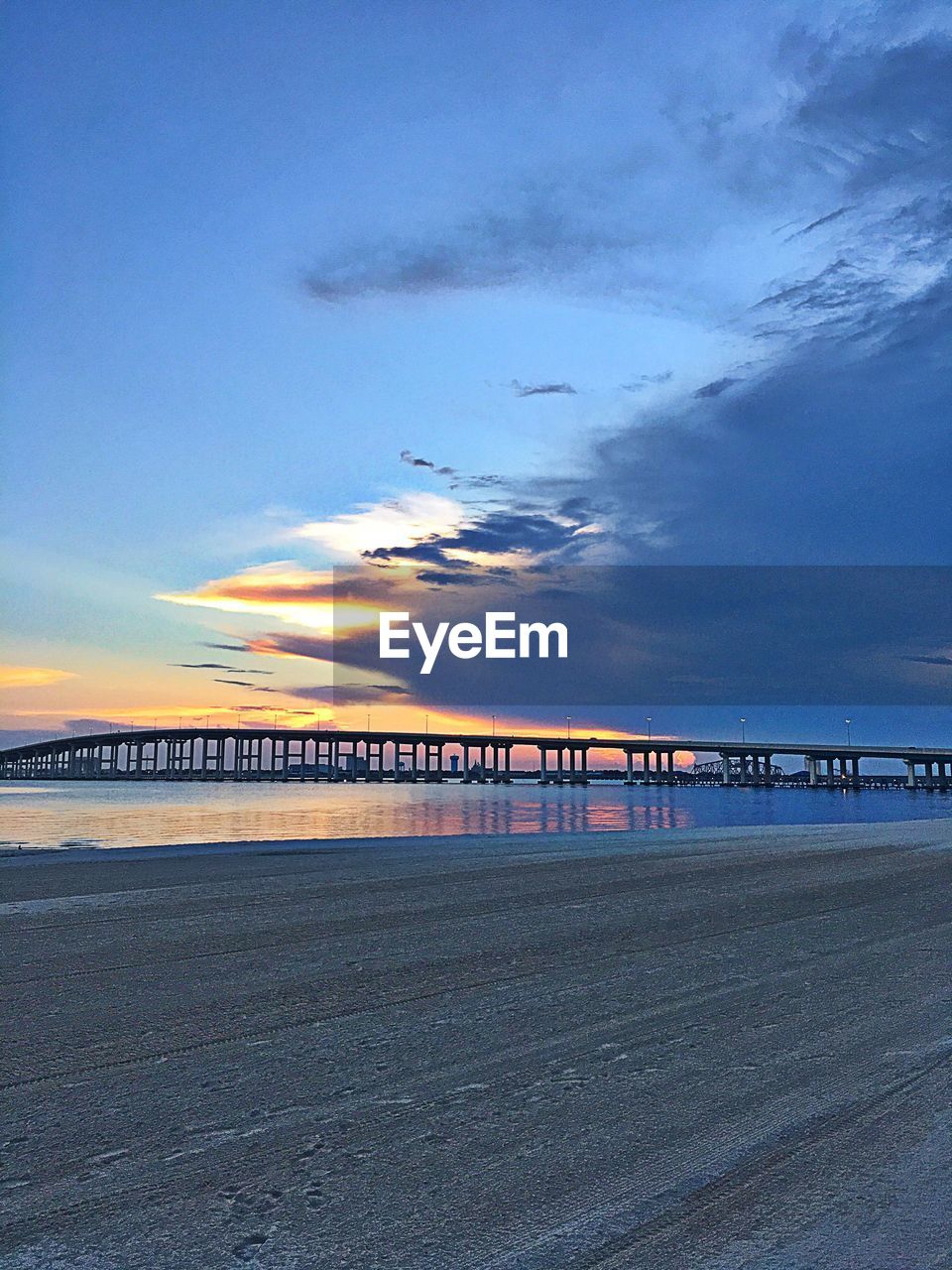 Bridge over sea against sky during sunset