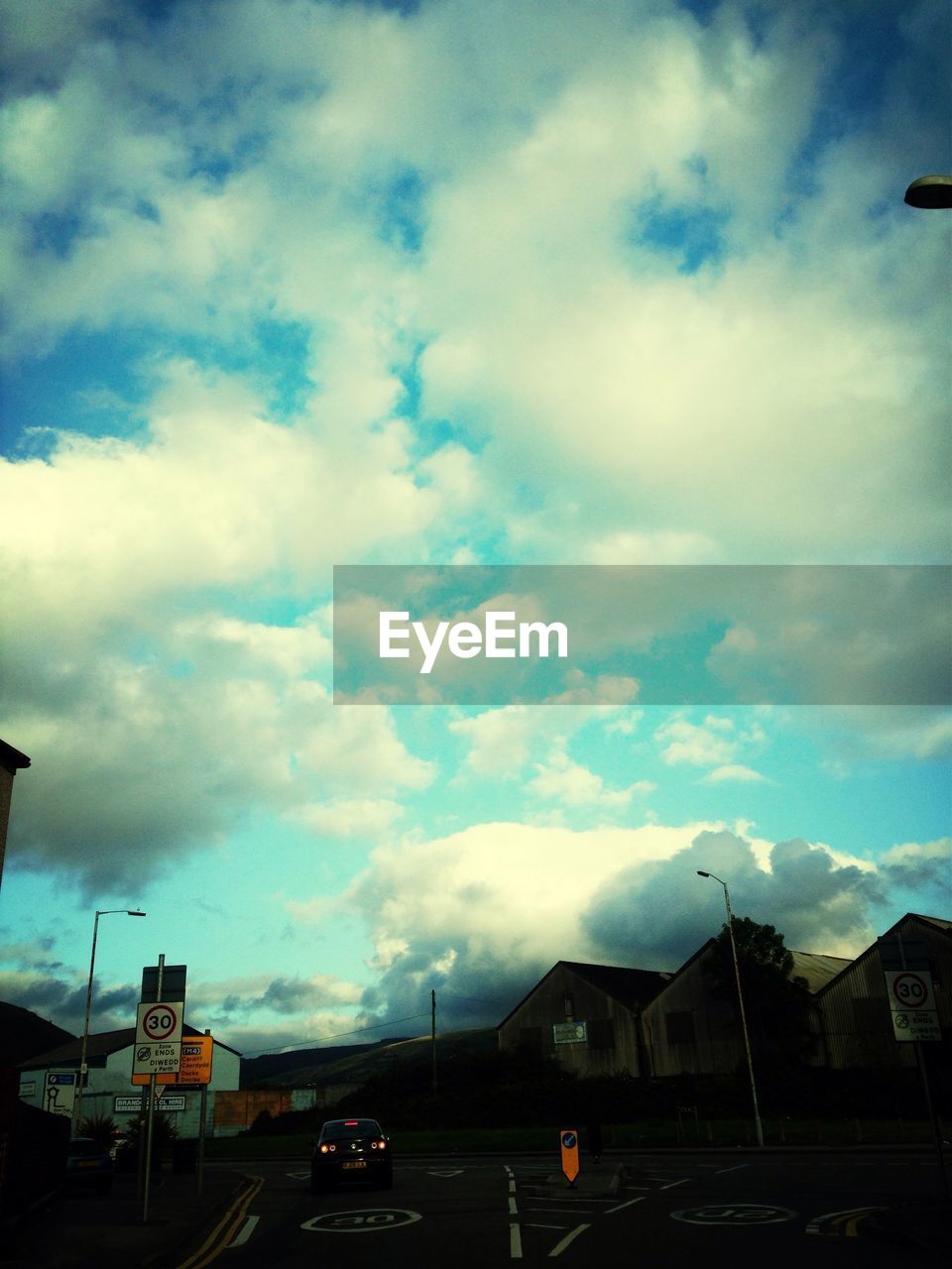 Street amidst houses against cloudy blue sky