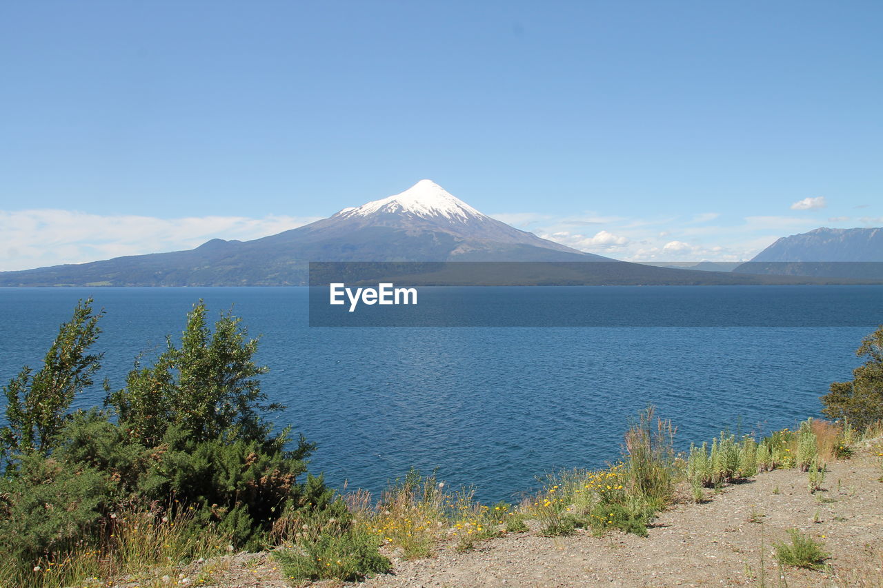 Scenic view of lake and mountains against sky on sunny day