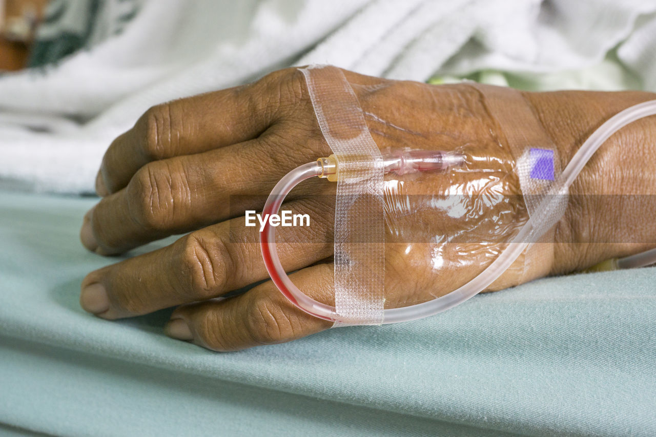 Cropped image of patient with iv drip on bed in hospital