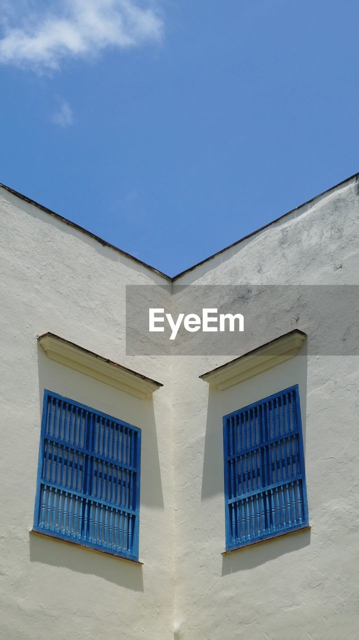 Low angle view  to blue shuttered building against blue sky