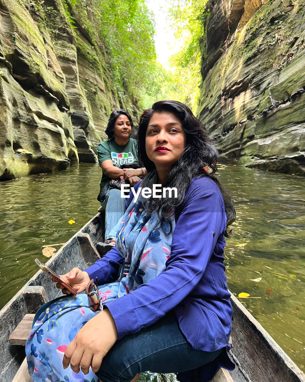 Portrait of young woman sitting by lake