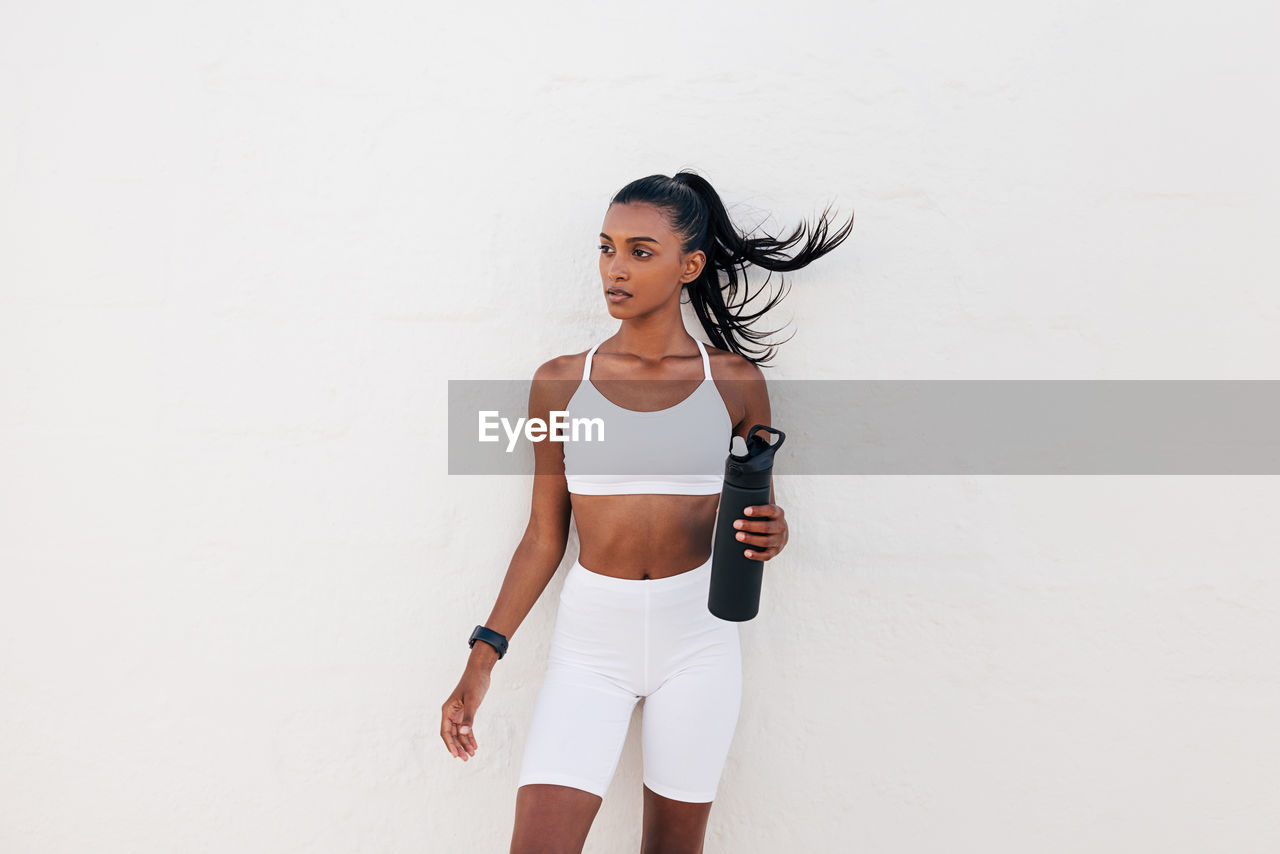 portrait of young woman with arms raised standing against white background