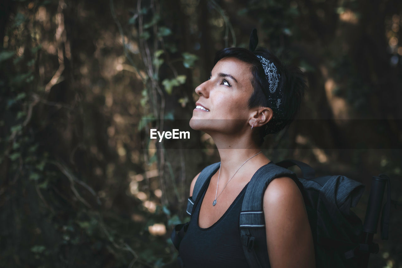 Woman looking away while standing in forest