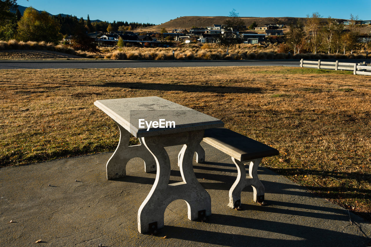 EMPTY BENCH IN PARK BY LAKE