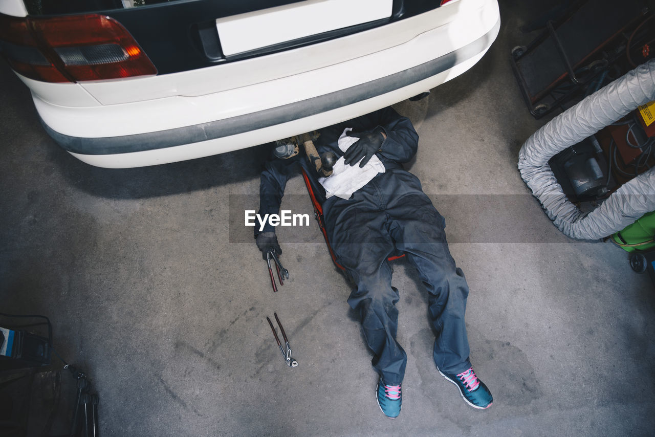 High angle view of mechanic repairing car in workshop