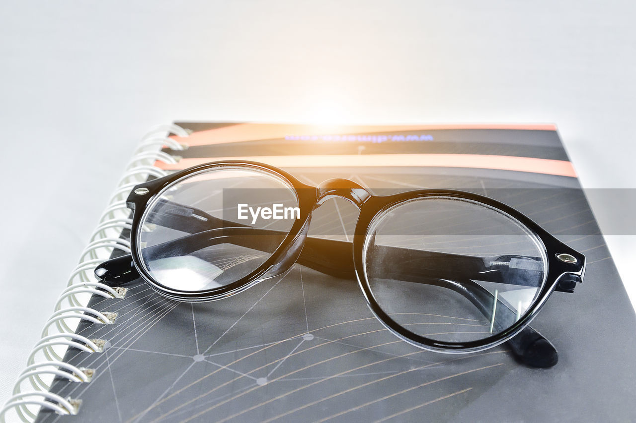 Close-up of eyeglasses on book against white background