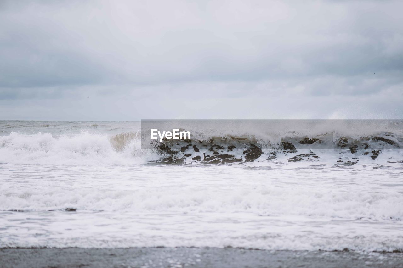 Scenic view of sea waves splashing against sky