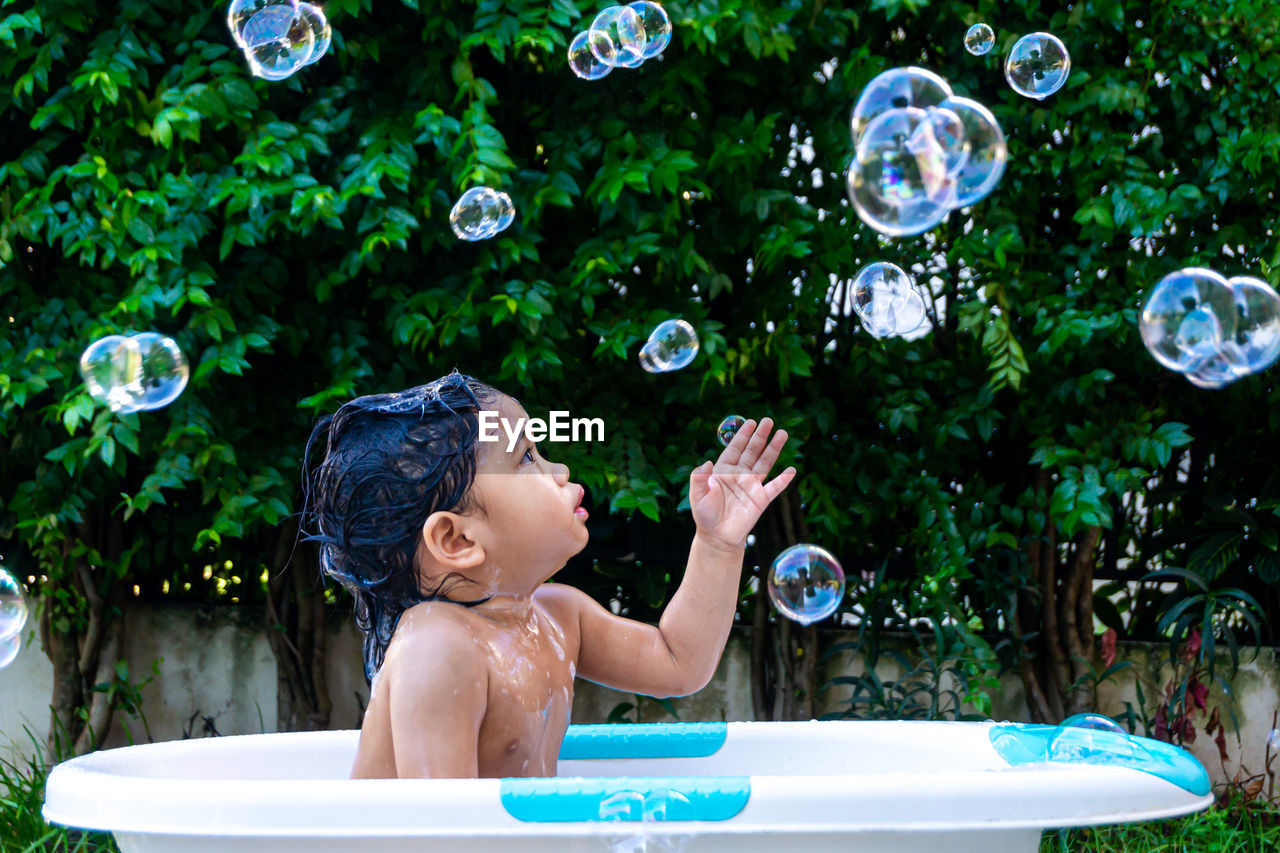 Full length of shirtless boy with bubbles