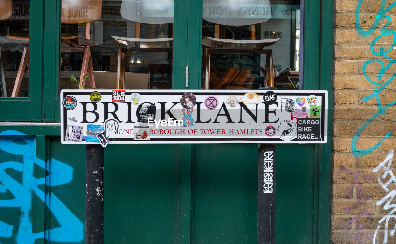 urban area, text, communication, architecture, western script, no people, sign, built structure, blue, green, building exterior, day, art, outdoors, street, graffiti, entrance, wall, door, city