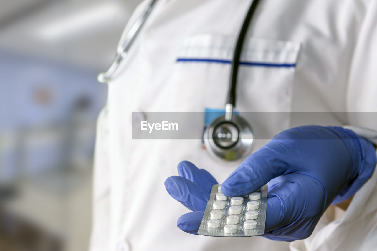 Midsection of doctor holding pills in hospital