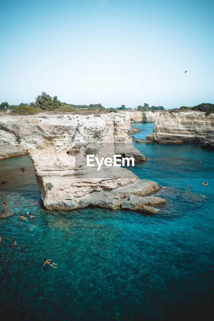 Rock formations in sea against clear blue sky