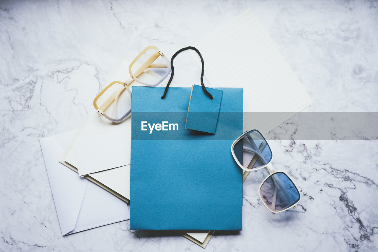 blue, glasses, eyeglasses, indoors, high angle view, no people, fashion accessory, still life, turquoise, studio shot, handbag, paper, copy space, fashion, art, table, sunglasses, group of objects, creativity