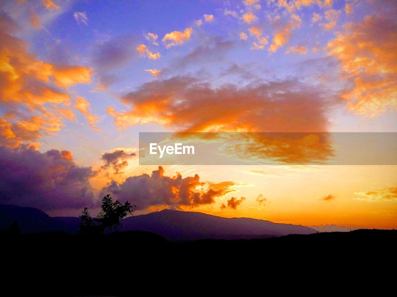 SCENIC VIEW OF SILHOUETTE MOUNTAINS AGAINST DRAMATIC SKY DURING SUNSET