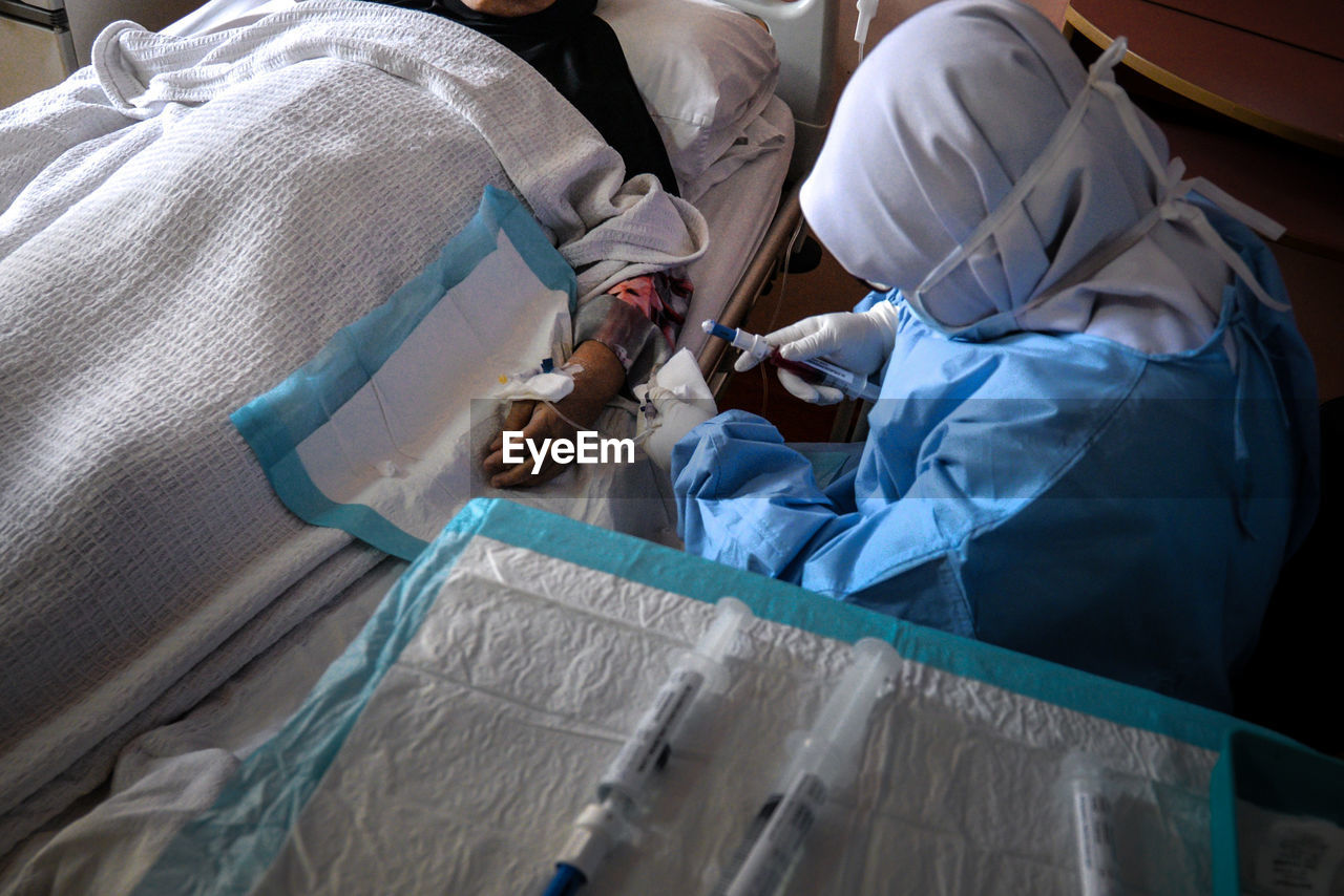 High angle view of doctor injecting syringe to patient at hospital