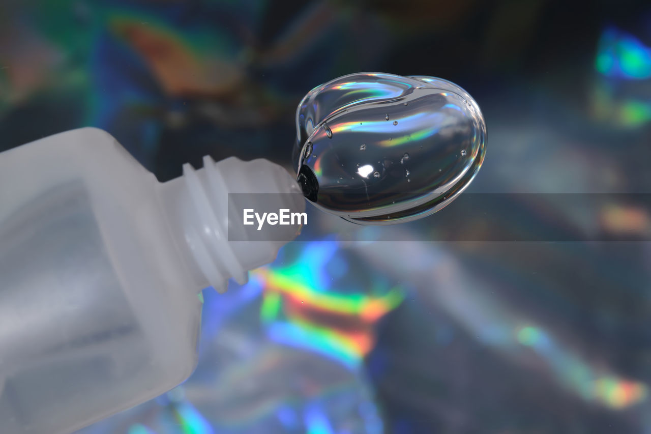 Hyaluronic gel or shower gel squeezed out of a bottle on a holographic background.