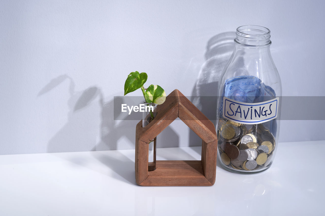 Hand made wooden house with saving jar near window