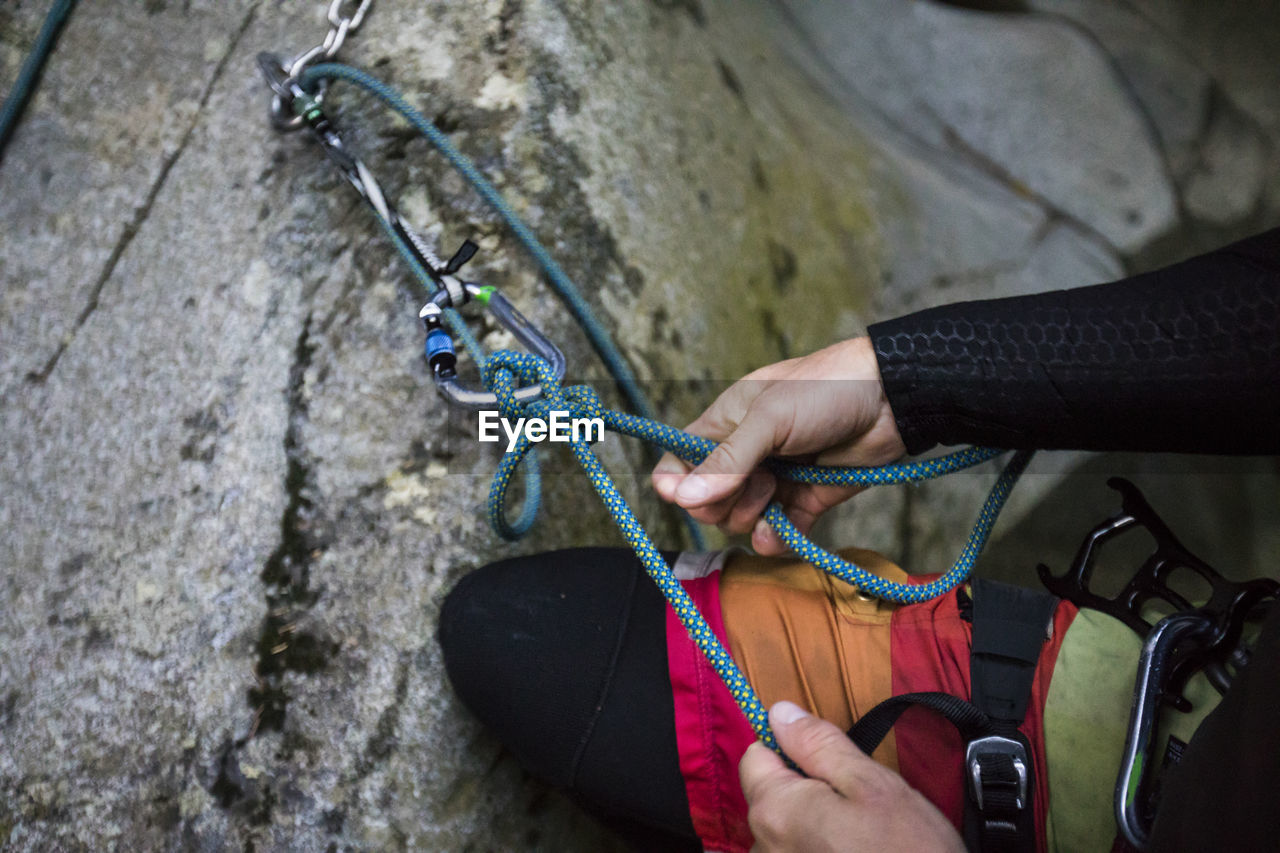 Detail view of climber tying rope for rappel, bolted route in canyon.