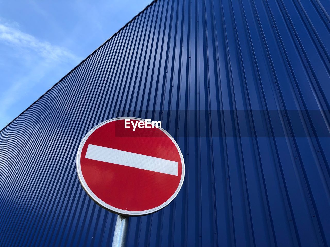 Low angle view of road sign against corrugated iron