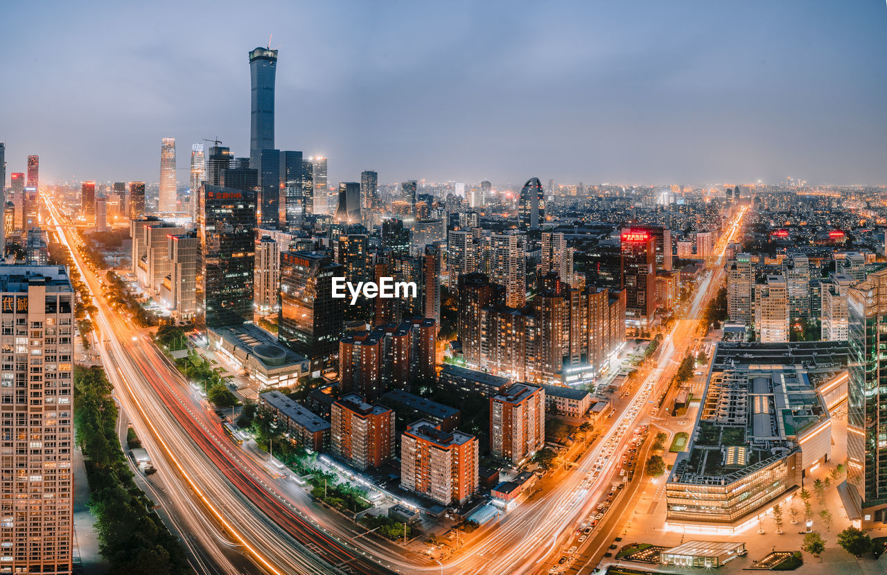 HIGH ANGLE VIEW OF ILLUMINATED CITY AGAINST SKY