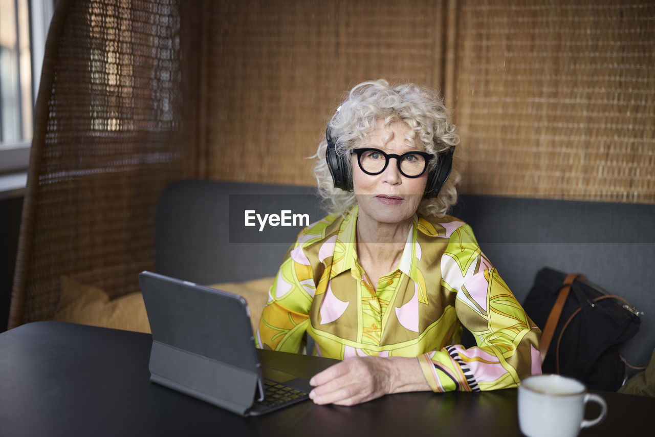 Portrait of senior woman with headphones using tablet