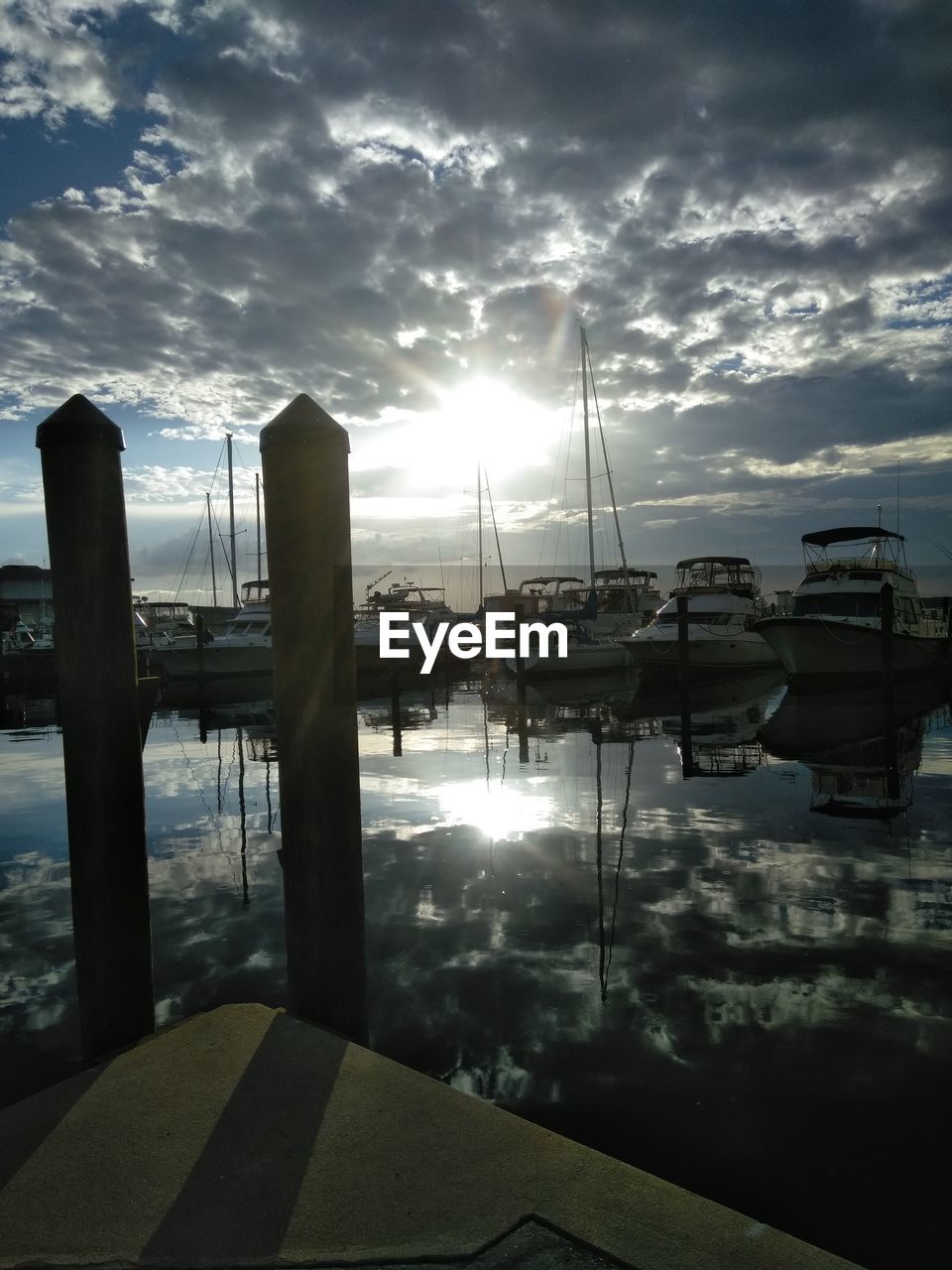 Sailboats moored at harbor against sky during sunset