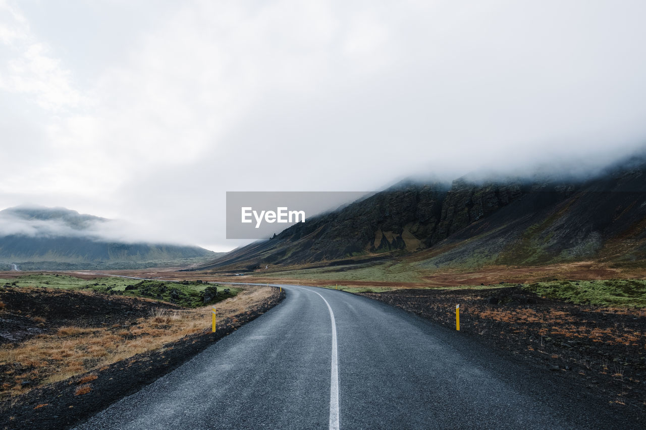 Diminishing perspective of empty road against cloudy sky