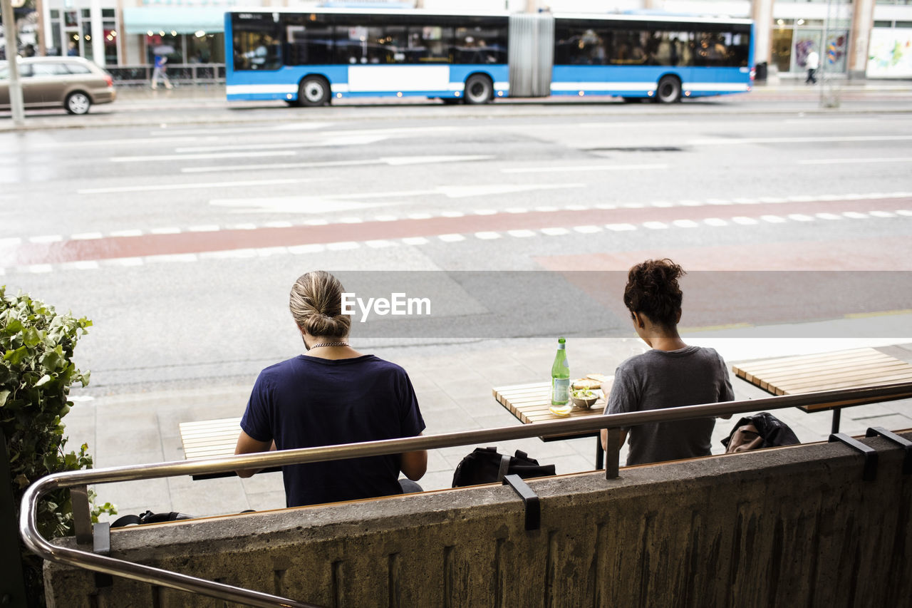 Rear view of man and woman sitting at sidewalk cafe in city