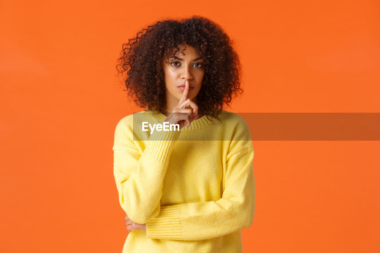 Portrait of woman against orange background