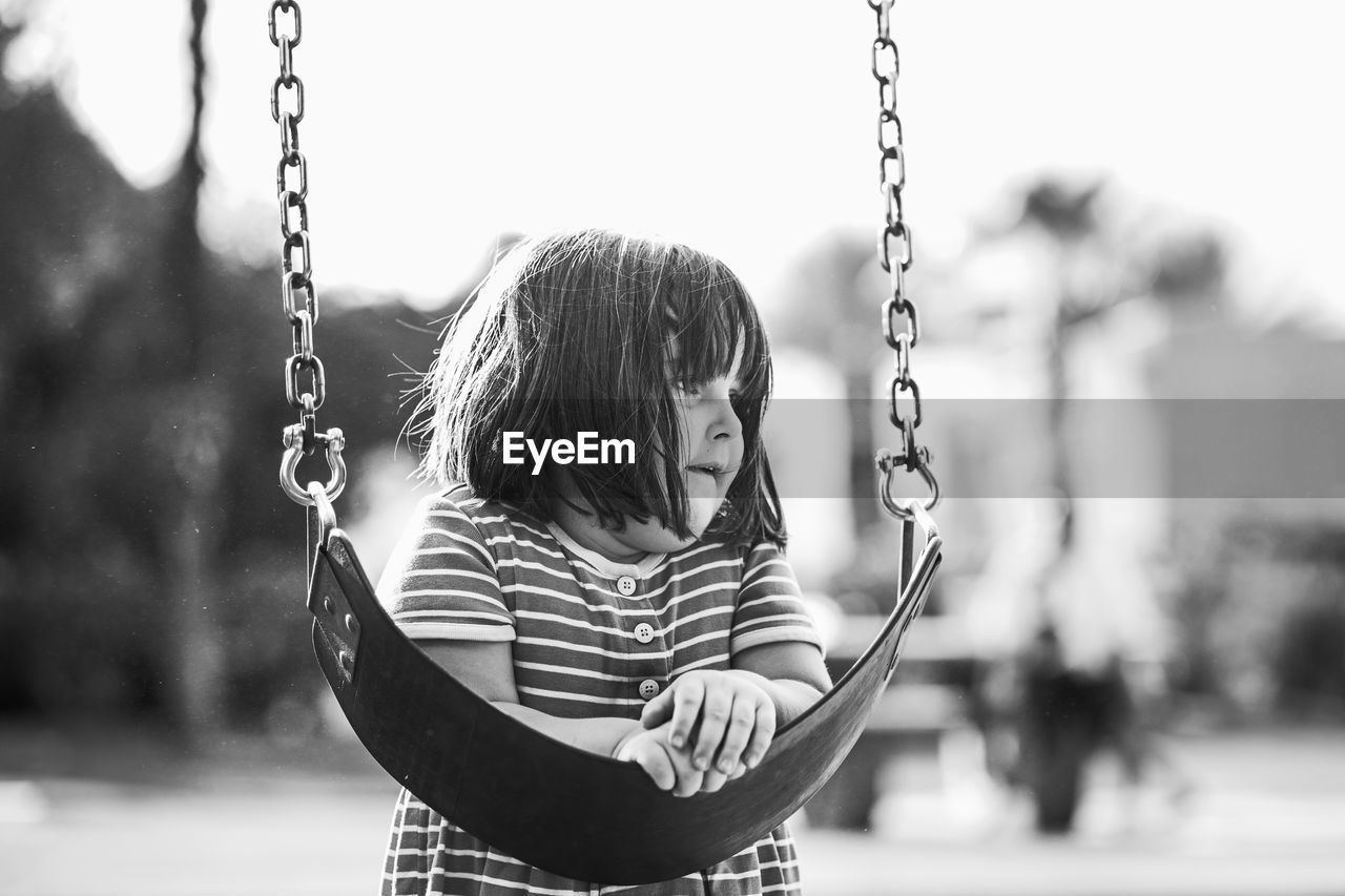 Close-up of girl leaning on swing at playground