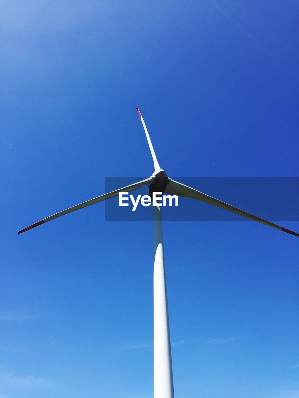 Low angle view of wind turbine against blue sky