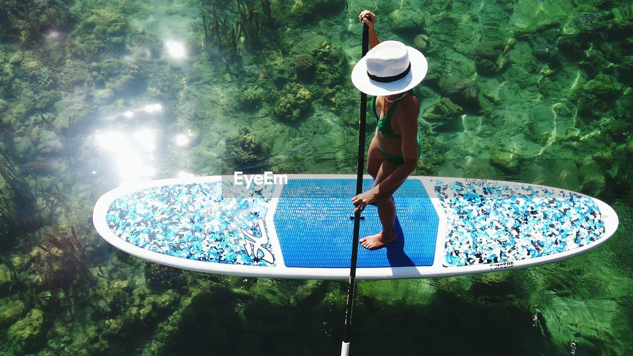 High angle view of woman paddleboarding in sea during sunny day