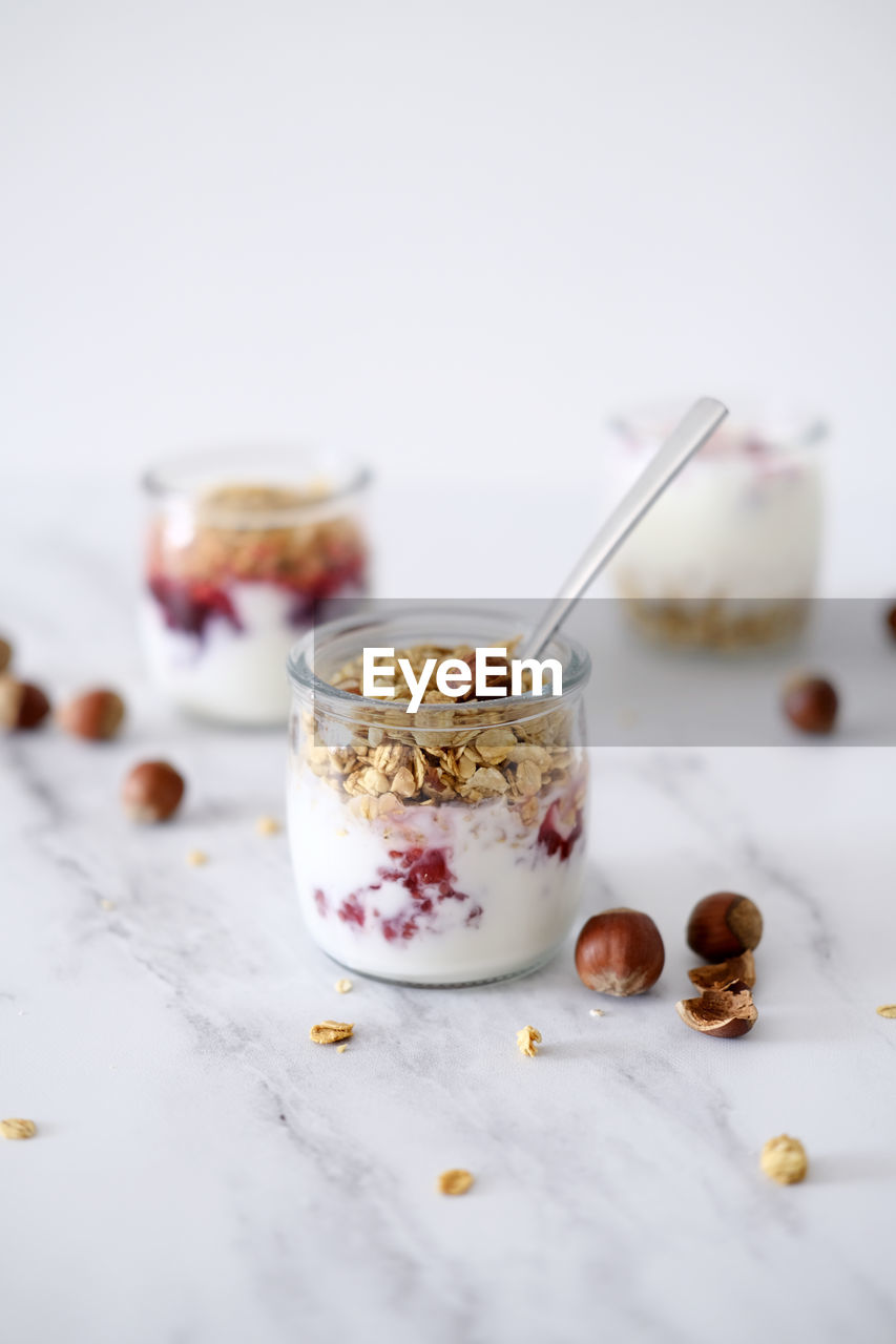 Oatmeal granola with greek yogurt and nuts strawberry muesli in jars on light background