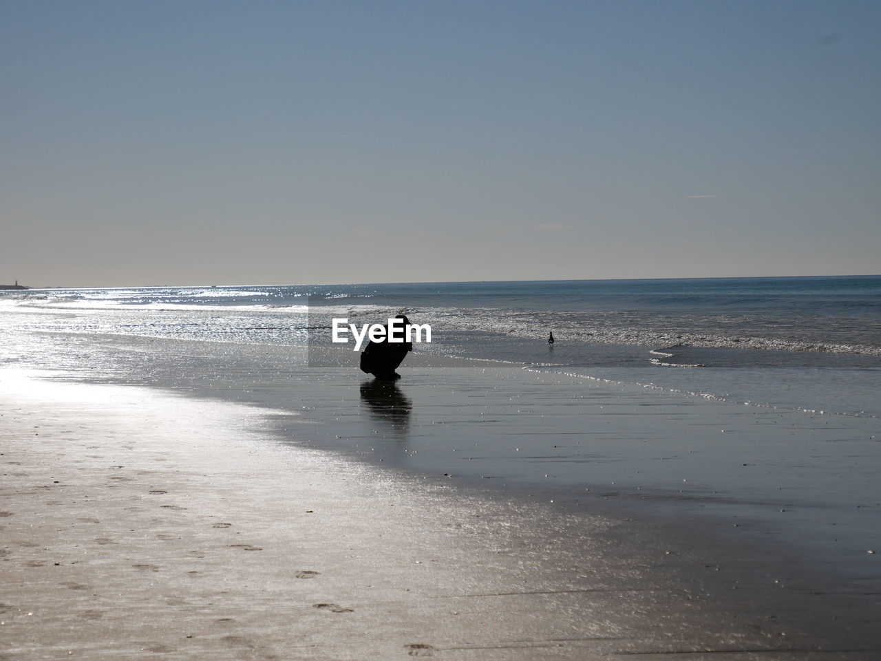 Photographer on beach against clear sky