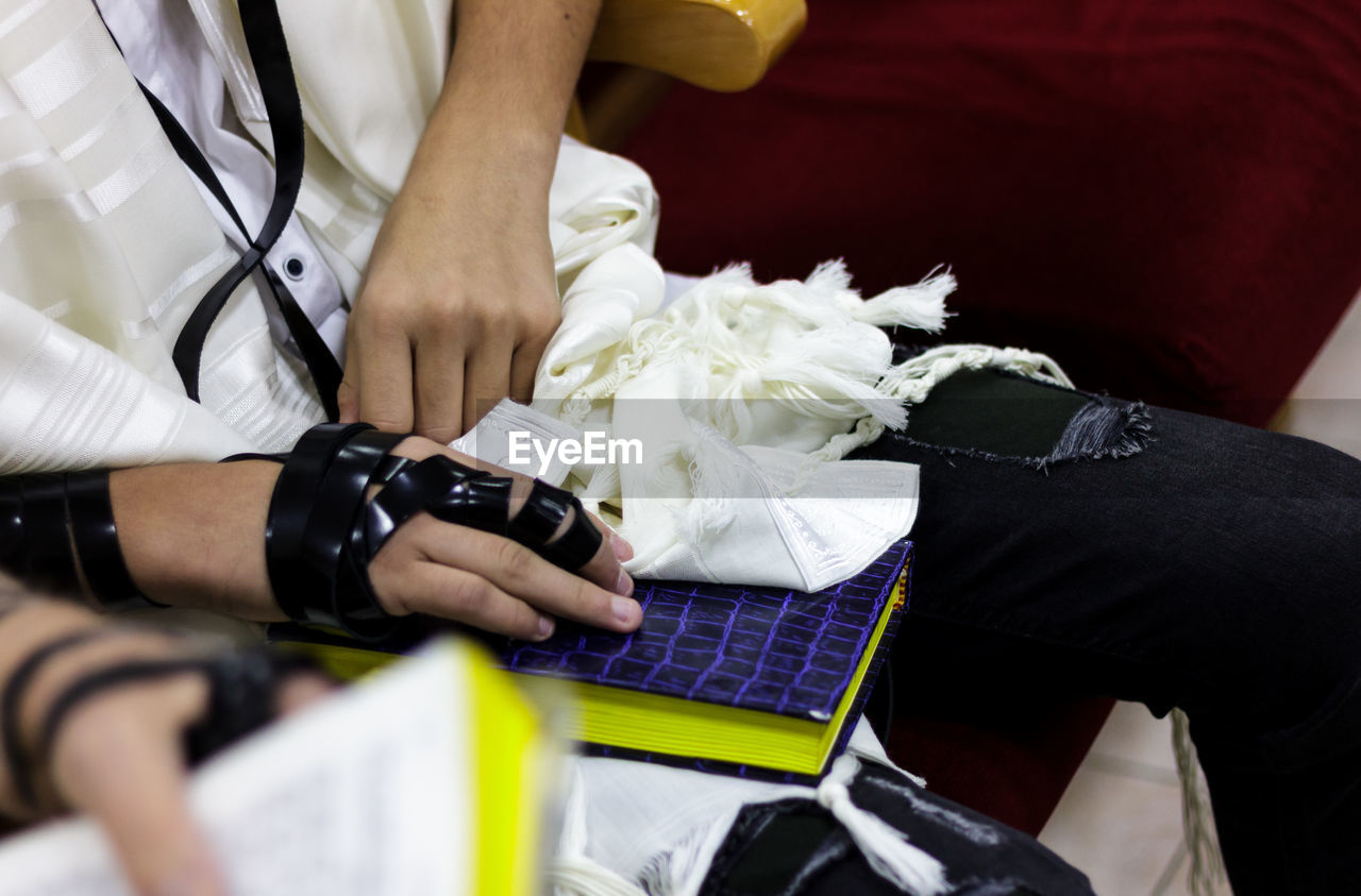 Midsection of man sitting with book