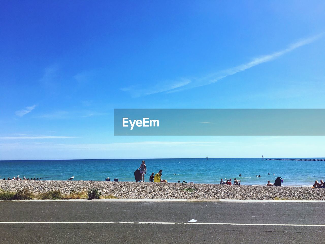 GROUP OF PEOPLE ON BEACH AGAINST BLUE SKY