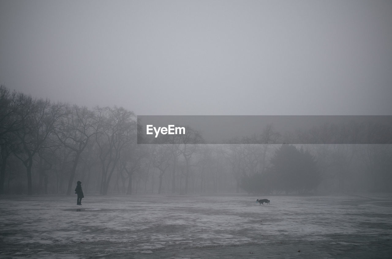 MAN STANDING ON SNOW COVERED LANDSCAPE DURING FOGGY WEATHER