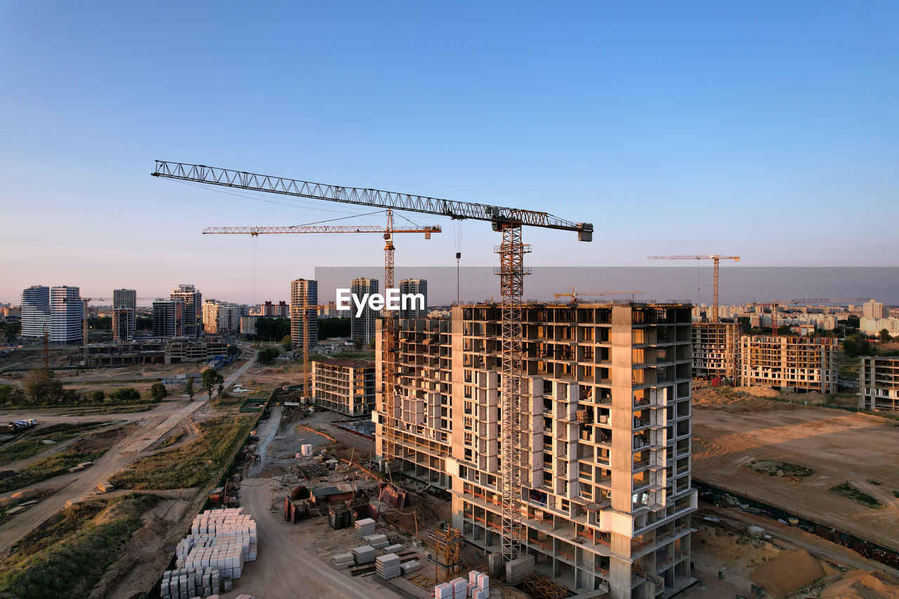 CRANE AT CONSTRUCTION SITE AGAINST BUILDINGS IN CITY