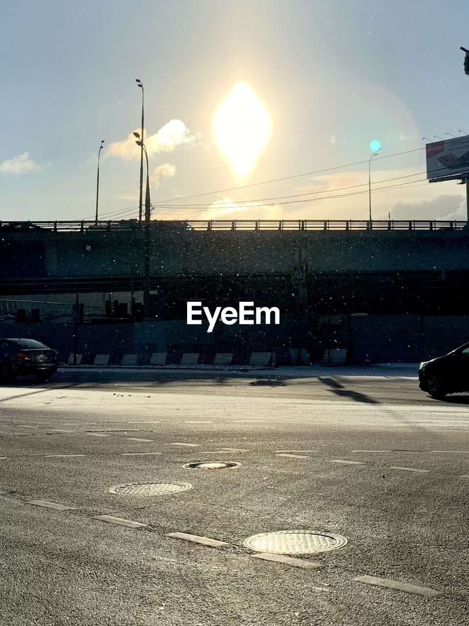 sky, transportation, road, mode of transportation, car, motor vehicle, nature, street, vehicle, architecture, sunlight, evening, city, no people, street light, land vehicle, built structure, cloud, sport venue, outdoors, stadium, sunset, light, reflection, parking lot, horizon