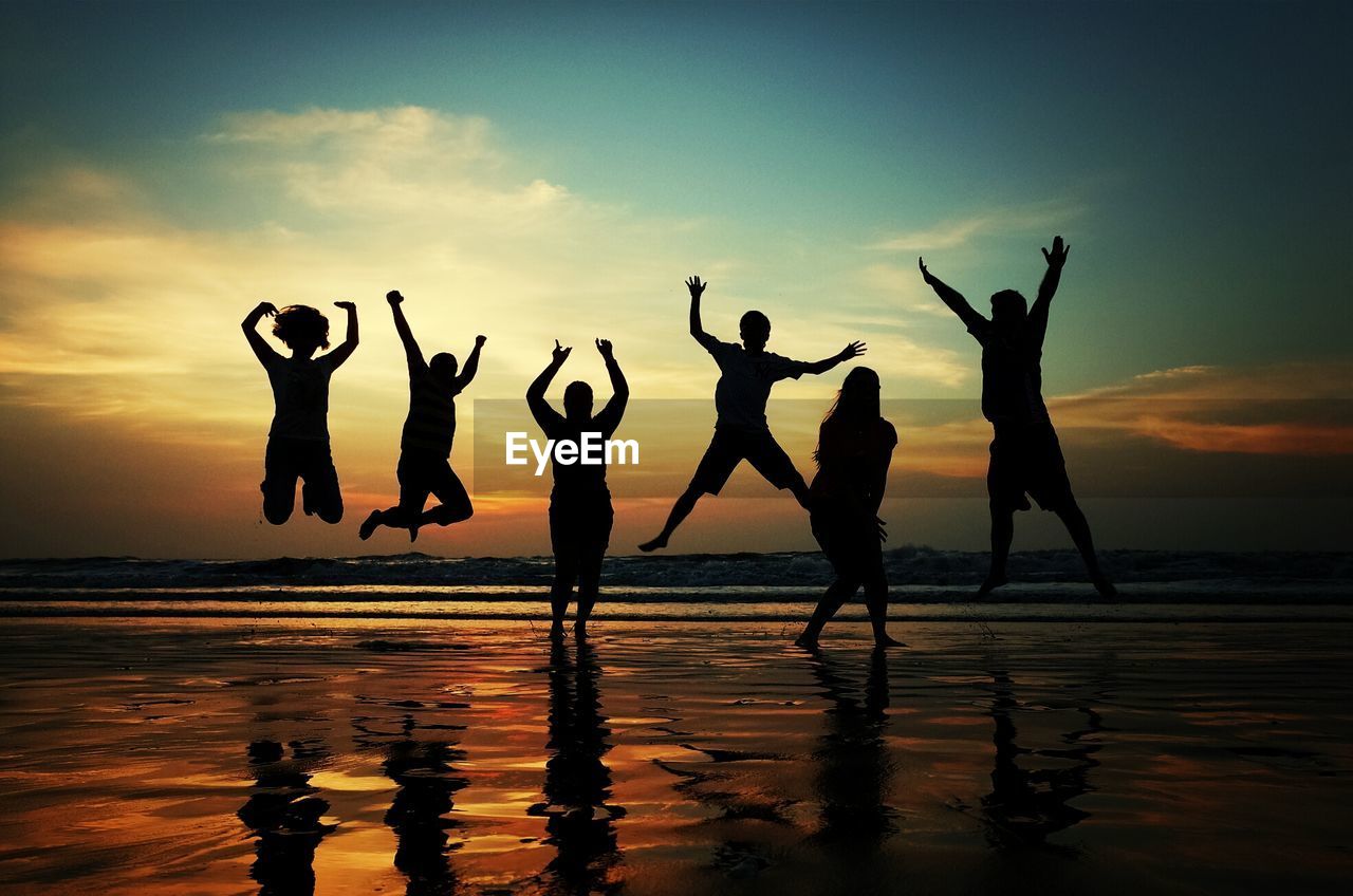 Group of silhouette people jumping on beach