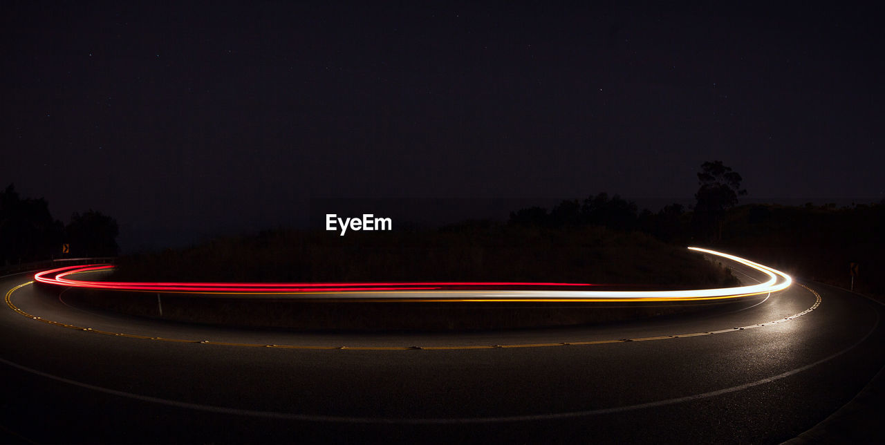 Light trails on road against sky at night